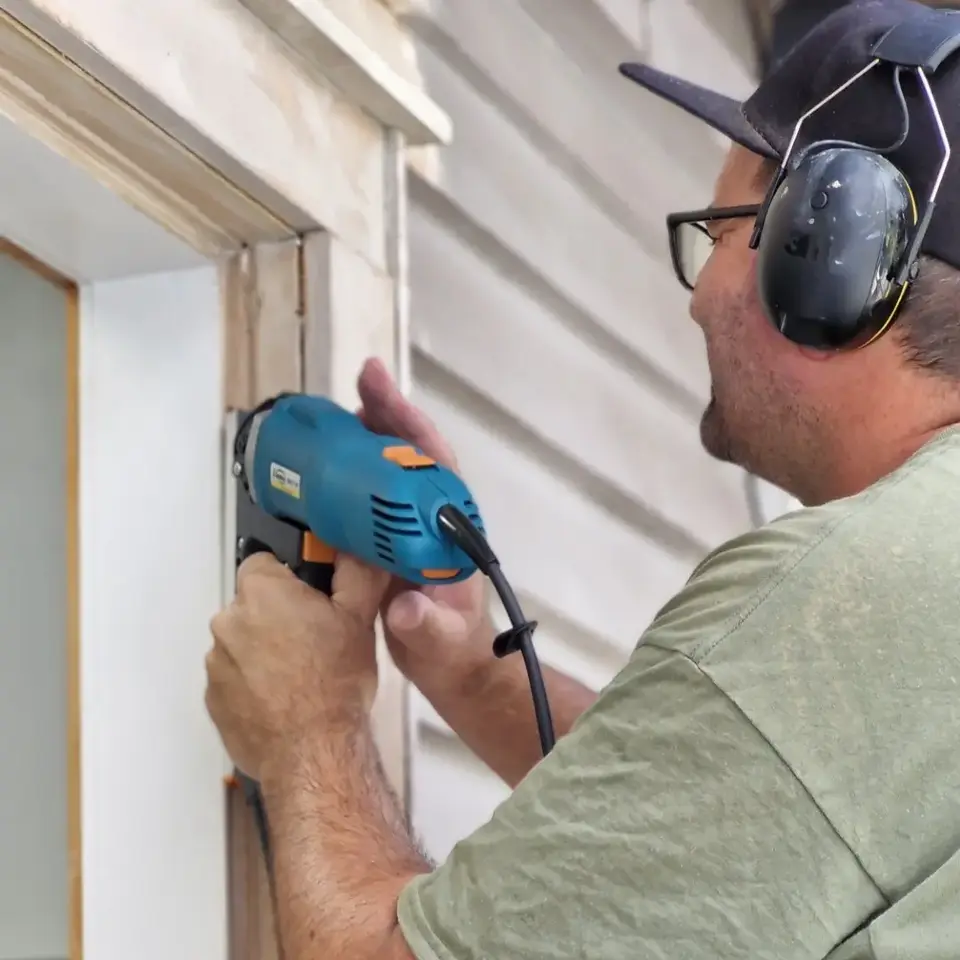 Ryan Bramwell from The Glaziers preparing an existing timber window for retrofit double glazing installation in an Auckland home
