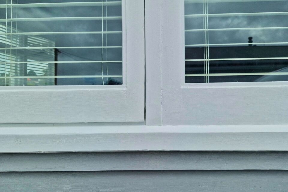 A close-up of a freshly restored wooden window frame with a smooth white finish and double glazing. The upgraded window enhances insulation, reduces noise, and improves energy efficiency. The Glaziers Ltd in Auckland specialises in retrofit double glazing for timber windows, preserving character while providing modern thermal performance.